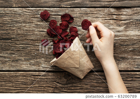 Home-made beet chips. Snacks are wrapped in a paper bag. Hand holds food bag. Handmade healthy vegetables chips 63200789