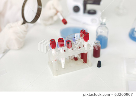 Scientist in coverall clothing is examining coronavirus sample in a laboratory 63200907