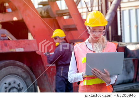Beautiful technician or worker in cargo shipping area work with laptop and the other is working Beautiful technician or worker in cargo shipping area work with laptop and the other is working 63200946