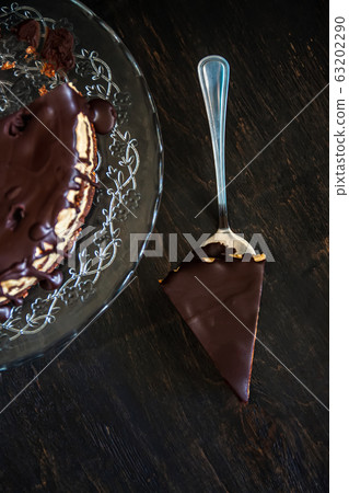Slice and chocolate cake layers with butter-cream-nut cream with chocolate drips on a glass stand on 63202290