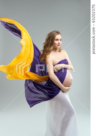 Pregnant woman covering breast and touching belly Pregnant woman covering breast and touching belly 63202370