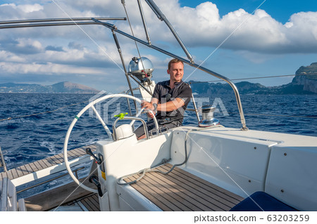 Sailor at the helm of modern sailing yacht Sailor at the helm of modern sailing yacht 63203259