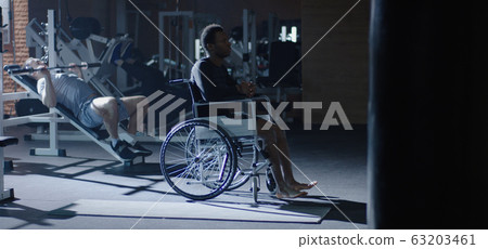 Wheelchair man sitting while others working out 63203461