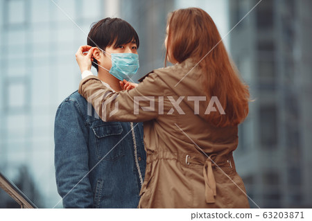 A woman and Chinese man are wearing protective masks 63203871