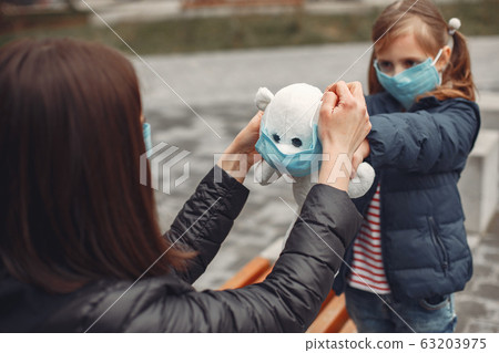 Woman in a disposable mask is teaching her child to wear a respirator 63203975
