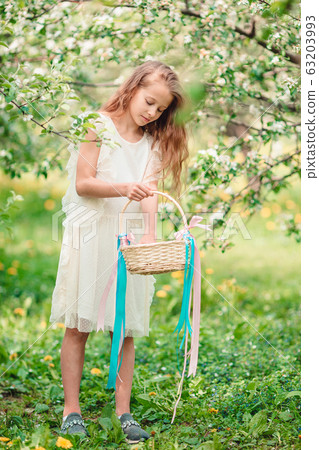 Adorable little girl in blooming apple garden on beautiful spring day 63203993