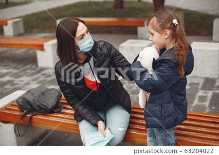 Woman in a disposable mask is teaching her child to wear a respirator 63204022