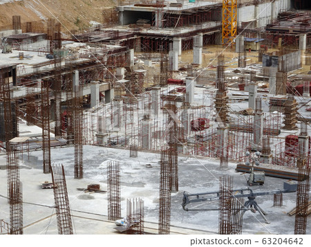 An aerial image of the construction site where the column is actively provided on the slab for the next level. Workers are working in stages. 63204642