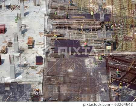 An aerial image of the construction site where the column is actively provided on the slab for the next level. Workers are working in stages. An aerial image of the construction site where the column is actively provided on the slab for the next level. Workers are working in stages. 63204648