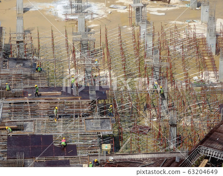 An aerial image of the construction site where the column is actively provided on the slab for the next level. Workers are working in stages. An aerial image of the construction site where the column is actively provided on the slab for the next level. Workers are working in stages. 63204649