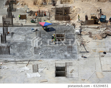 An aerial image of the construction site where the column is actively provided on the slab for the next level. Workers are working in stages. An aerial image of the construction site where the column is actively provided on the slab for the next level. Workers are working in stages. 63204651