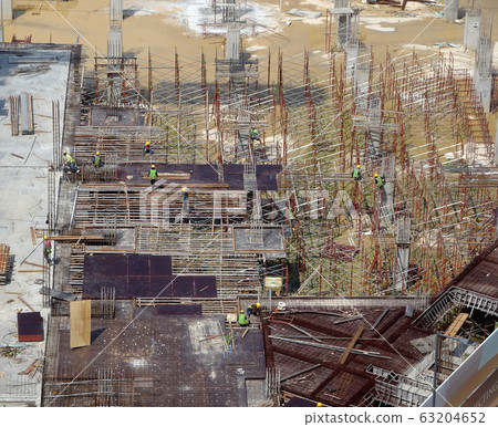 An aerial image of the construction site where the column is actively provided on the slab for the next level. Workers are working in stages. An aerial image of the construction site where the column is actively provided on the slab for the next level. Workers are working in stages. 63204652