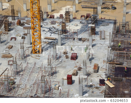 An aerial image of the construction site where the column is actively provided on the slab for the next level. Workers are working in stages. 63204653