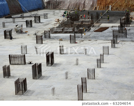 An aerial image of the construction site where the column is actively provided on the slab for the next level. Workers are working in stages. An aerial image of the construction site where the column is actively provided on the slab for the next level. Workers are working in stages. 63204654