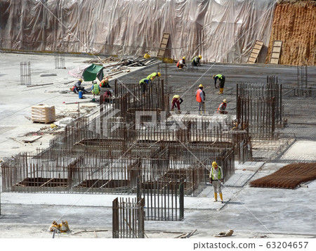 An aerial image of the construction site where the column is actively provided on the slab for the next level. Workers are working in stages. An aerial image of the construction site where the column is actively provided on the slab for the next level. Workers are working in stages. 63204657