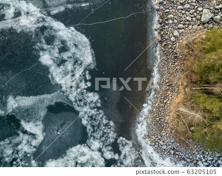 Icy patterns on ice cover of a frozen lake at shore 63205105