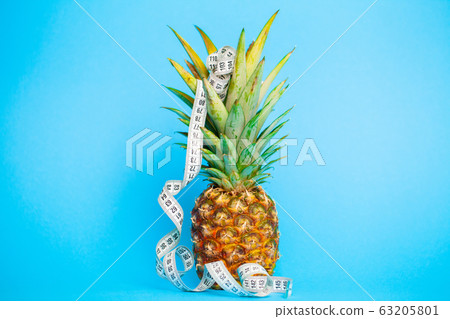 Ripe pineapple with measuring tape on a blue background 63205801