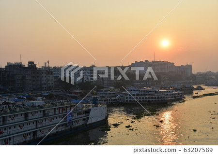 Dhaka in Bangladesh Beautiful sunrise and old cityscape Passenger ship that stops along the Brigonga River Large and small boats crossing the river 63207589