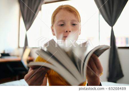 Young Redhead Girl Studying And Looking Through Book Young Redhead Girl Studying And Looking Through Book 63208489