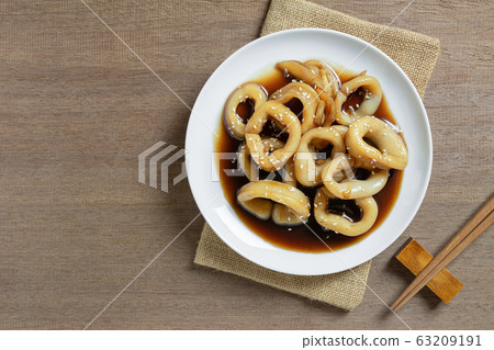 top view of stir fried squid with teriyaki sauce in a ceramic dish on wooden table. 63209191