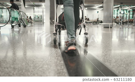 woman carry luggage cart walk at airport terminal 63211180