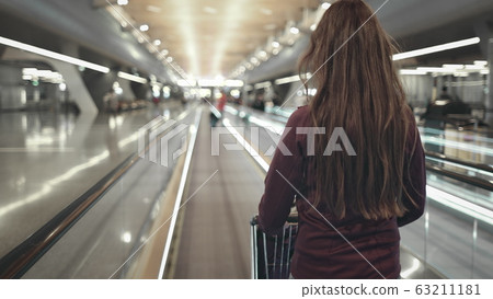 girl with luggage cart walking airport speedwalk 63211181