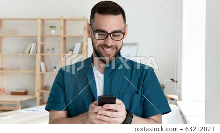 Young smiling company worker looking at mobile phone screen. Young smiling company worker looking at mobile phone screen. 63212021