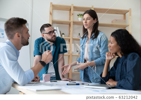 Focused young diverse employees listening to motivated skilled female professional. Focused young diverse employees listening to motivated skilled female professional. 63212042