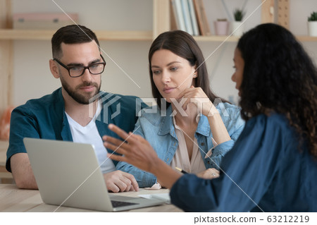 Mixed race financial advisor showing presentation on laptop to clients. Mixed race financial advisor showing presentation on laptop to clients. 63212219