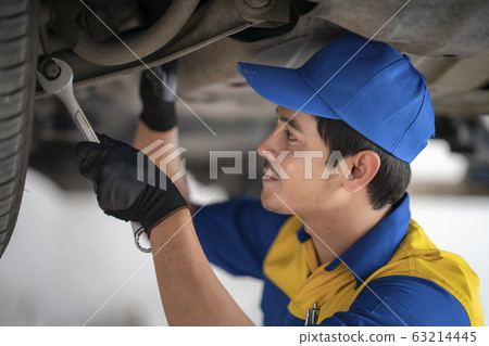 Asian worker in uniform working in car engine 63214445