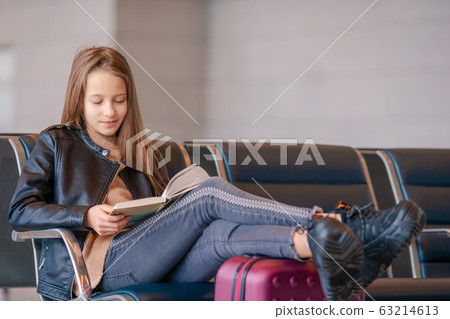 Adorable little girl at airport in big international airport near window Adorable little girl at airport in big international airport near window 63214613