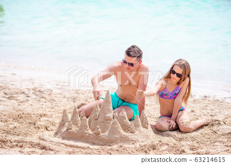 Father and kid making sand castle at tropical beach. Family playing with beach toys Father and kid making sand castle at tropical beach. Family playing with beach toys 63214615