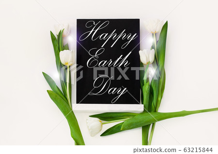 Happy Earth Day April 22 greeting message sign on black chalk board with tulip flowers on white background. World ecology concept card.Saving environment, save clean planet.Blackboard with text,banner Happy Earth Day April 22 greeting message sign on black chalk board with tulip flowers on white background. World ecology concept card.Saving environment, save clean planet.Blackboard with text,banner 63215844