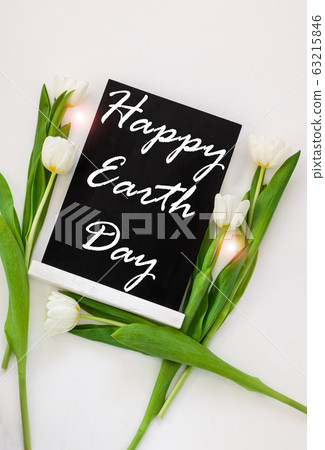 Happy Earth Day April 22 greeting message sign on black chalk board with tulip flowers on white background. World ecology concept card.Saving environment, save clean planet.Blackboard with text,banner 63215846