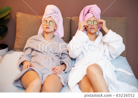 Two girlfriends with towels on their heads, doing spa treatments at home in bed 63216552