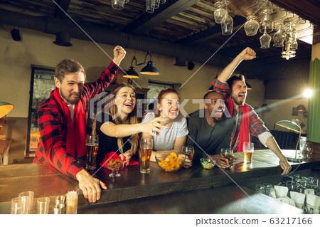 Sport fans cheering at bar, pub and drinking beer while championship, competition is going 63217166
