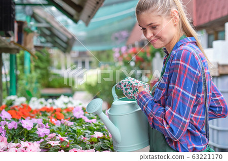 Female florist or gardener in flower shop or Female florist or gardener in flower shop or 63221170