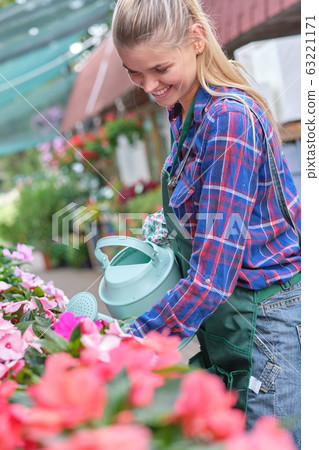 Female florist or gardener in flower shop or Female florist or gardener in flower shop or 63221171