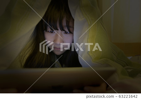A child looking at a tablet PC in a futon 63221642