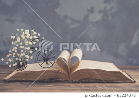 Old opened book, heart shaped paper sheets, iron 63224378