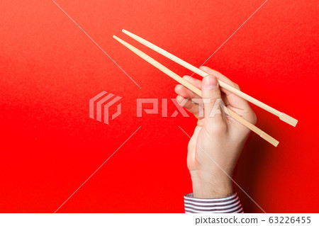 Boy's hand showing chopsticks on red background. Boy's hand showing chopsticks on red background. 63226455