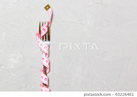 Close up of fork wrapped with tape measure on gray Close up of fork wrapped with tape measure on gray 63226461