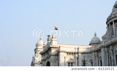 Indian National Flag floating over Victoria Memorial, an iconic structure of old Imperial British Raj 63226515