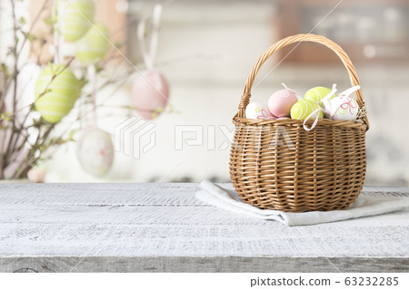 Wicker basket with easter colorful eggs on table top Wicker basket with easter colorful eggs on table top 63232285