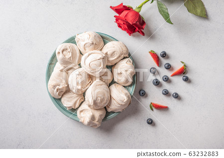 Homemade popular dessert meringue on a plate on white background. Nearby are strawberry and Homemade popular dessert meringue on a plate on white background. Nearby are strawberry and 63232883
