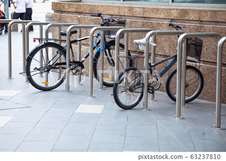 Bicycle top tubes are securely chained, by chain links and locks, to the metal bike racks 63237810