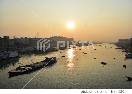 Dhaka in Bangladesh Beautiful sunrise and old cityscape Passenger ship that stops along the Brigonga River Large and small boats crossing the river Dhaka in Bangladesh Beautiful sunrise and old cityscape Passenger ship that stops along the Brigonga River Large and small boats crossing the river 63238024