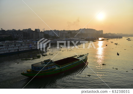 Dhaka in Bangladesh Beautiful sunrise and old cityscape Passenger ship that stops along the Brigonga River Large and small boats crossing the river 63238031