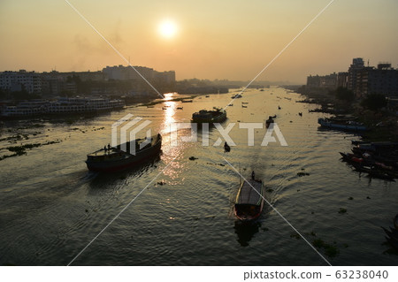 Dhaka in Bangladesh Beautiful sunrise and old cityscape Passenger ship that stops along the Brigonga River Large and small boats crossing the river Dhaka in Bangladesh Beautiful sunrise and old cityscape Passenger ship that stops along the Brigonga River Large and small boats crossing the river 63238040