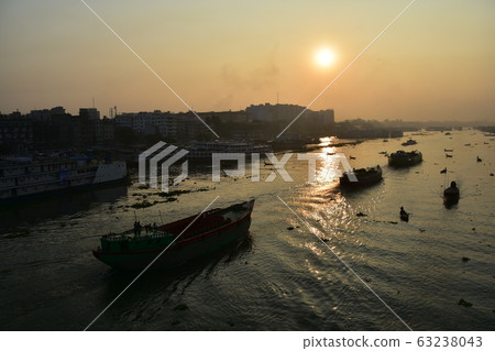 Dhaka in Bangladesh Beautiful sunrise and old cityscape Passenger ship that stops along the Brigonga River Large and small boats crossing the river 63238043